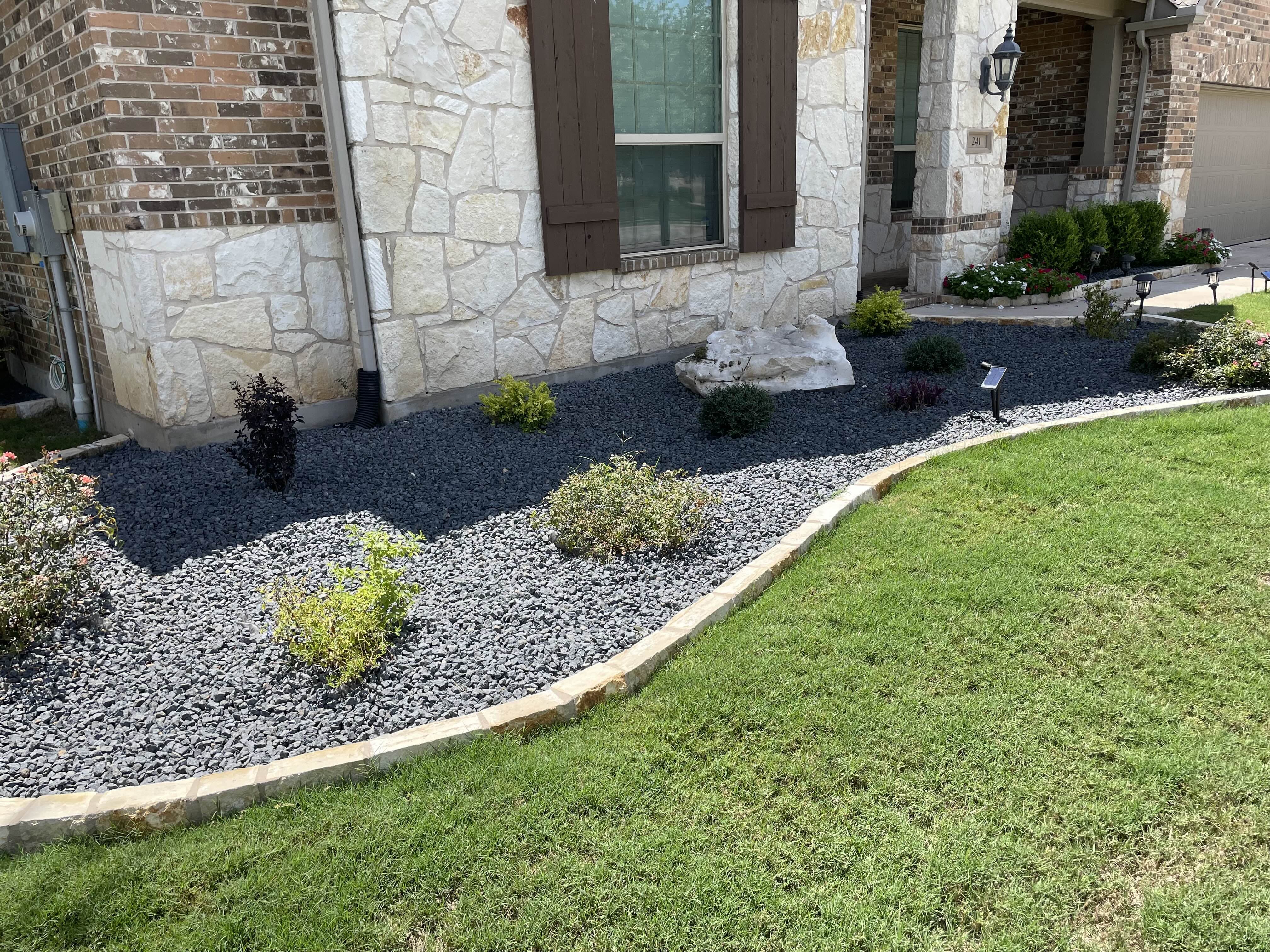After - This flower bed went from sparse and patchy to sharp and low-maintenance with the addition of sleek black rock, creating a bold contrast that highlights the plants and elevates the home's curb appeal.