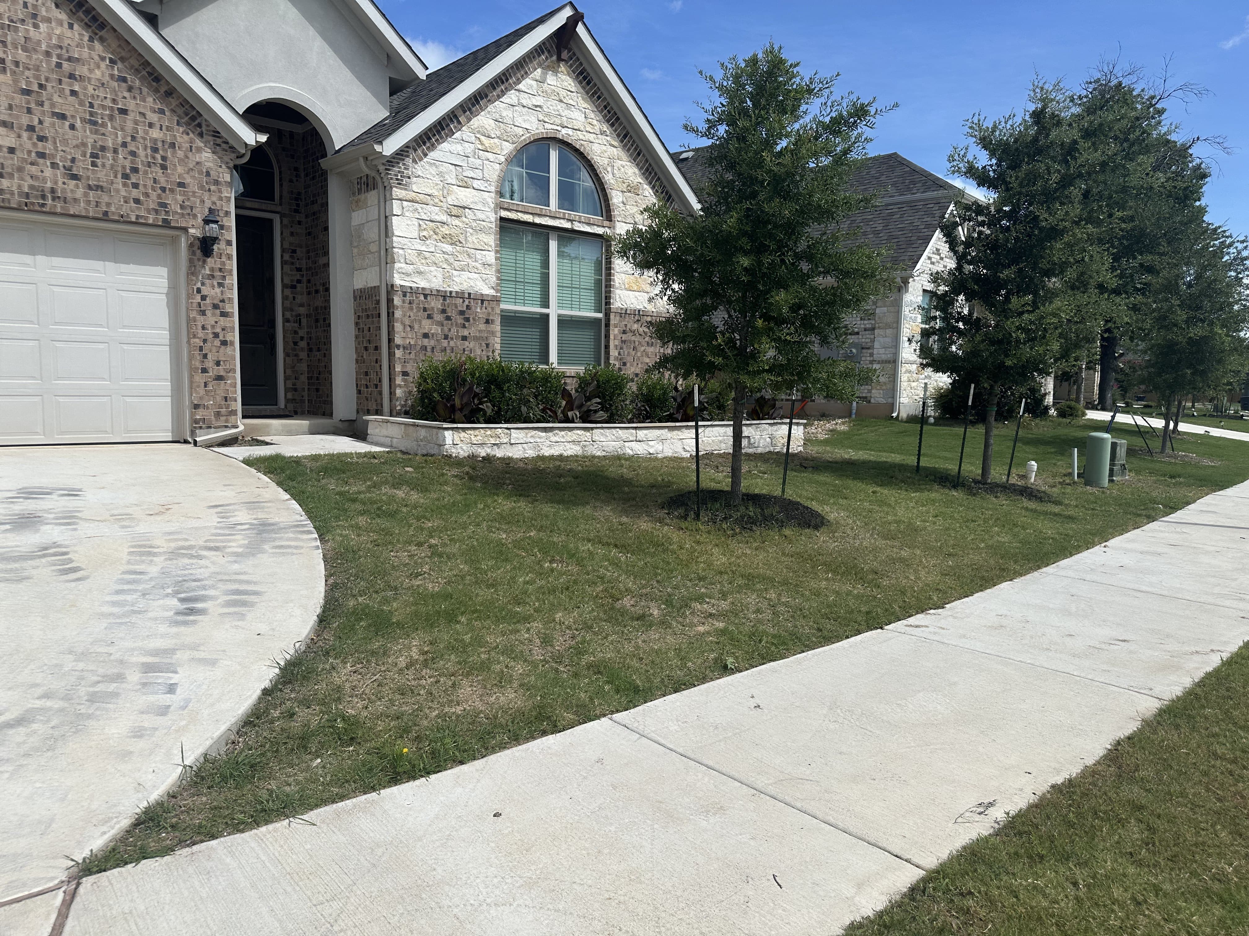 After - Added new shrubbery to enhance the color as well as a limestone wall to modernize the astetic of the yard and match the house. A fresh layer of black mulch added to retain moisture and to improve the look.