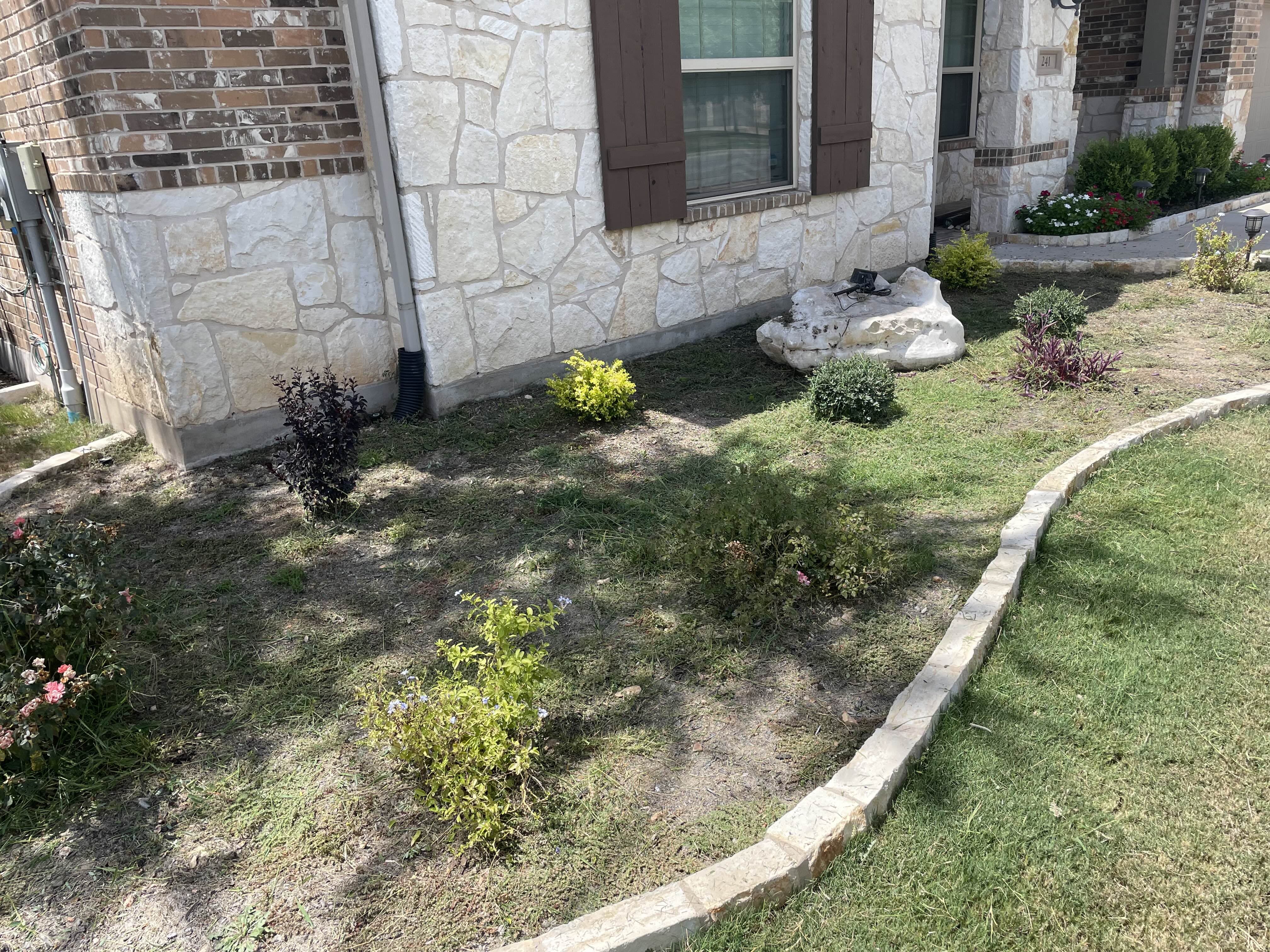 Before - This flower bed went from sparse and patchy to sharp and low-maintenance with the addition of sleek black rock, creating a bold contrast that highlights the plants and elevates the home's curb appeal.